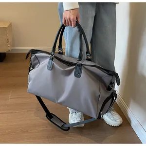Detail shot of a large grey nylon travel bag carried by a model in a minimal room