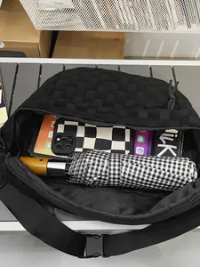 Large black woven crossbody chest bag showing spacious interior with tablet and umbrella