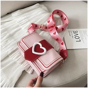 Dettaglio della borsa a tracolla rosa e rossa con fibbia a cuore e tracolla larga