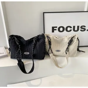 Détail de sacs fourre-tout plissés avec bandoulières en corde noir et crème sur socle