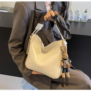 Detail van beige emmertas met een kleurrijke geweven riem en schattige konijnenhanger