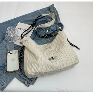 Détail du sac cabas plissé crème avec bandoulière en corde tressée et tissu texturé