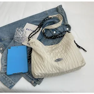 Détail d'un sac à bandoulière plissé blanc cassé avec une sangle en corde tissée