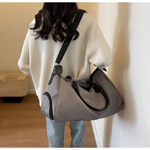 Detail view of large gray duffle bag with black straps and side shoe compartment