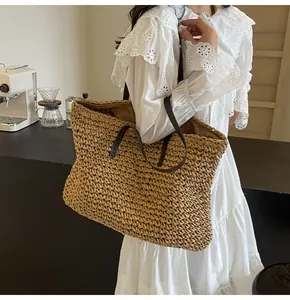 Detalle de textura de bolso tote de paja tejida con asas de cuero negro para el verano