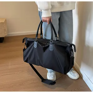 Large capacity black travel duffel bag with leather handles and adjustable shoulder strap