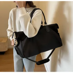 Detail of black travel bag showing smooth nylon fabric and detachable shoulder strap