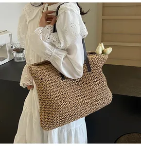 Primer plano de un bolso tote de paja tejida con correas marrones y decoración de tulipanes