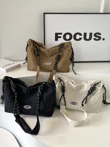 Trois sacs cabas plissés avec cordon en marron, noir et beige sur des marches blanches