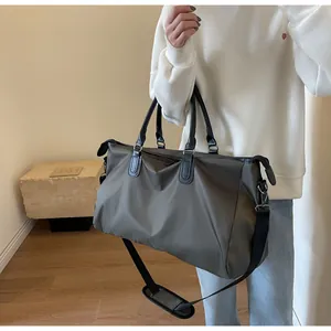 Detail of grey travel duffel bag with leather handles and padded shoulder strap