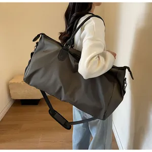 Close-up of a large grey nylon travel bag with shoulder strap worn by a person