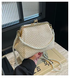 Close-up of cream woven shell bag with vintage gold clasp and pearl bead shoulder strap