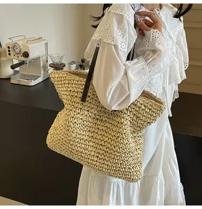 Detalle del bolso tote de paja tejida con correas de cuero marrón en un entorno de estilo moderno