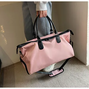 Pink travel bag with black handles and detachable shoulder strap in a minimalist room