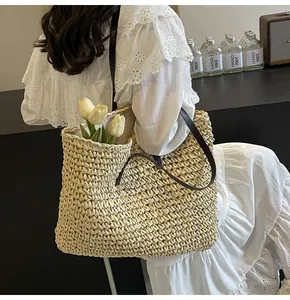 Detalle de bolso tote de paja tejida con correa de cuero marrón y tulipanes decorativos