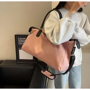 Pink large-capacity travel bag with black adjustable shoulder strap worn by female model