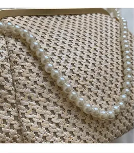 Close-up of woven raffia handbag with elegant pearl handle and golden metal clasp
