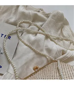Detailed close-up of woven straw bag texture featuring an elegant pearl chain strap