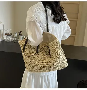 Detalle del bolso tote grande de paja trenzada con asas de cuero marrón en modelo