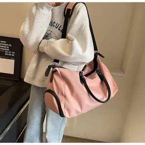 Pink duffel bag detail showing a side shoe compartment and adjustable shoulder straps