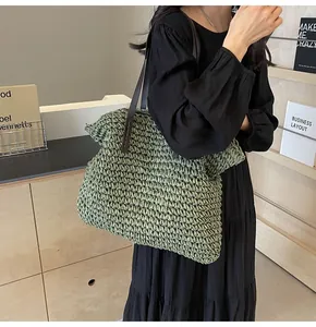 Detalle de bolso tote de paja tejida con correas de cuero marrón y textura