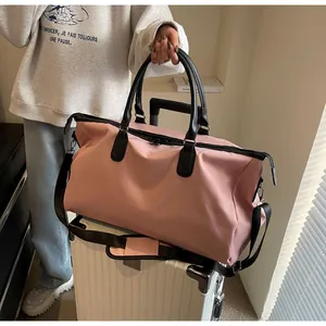 Pink travel duffel bag with black straps mounted on a white suitcase handle for easy transport