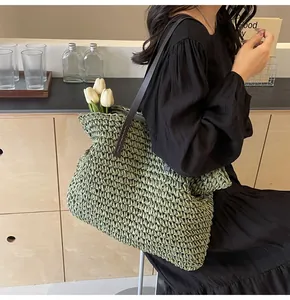 Detalle de textura tejida a mano y correa de cuero marrón de un bolso de paja verde
