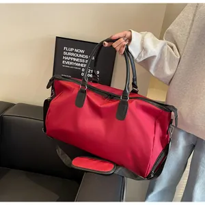 Detail of red travel bag with black handles and adjustable shoulder strap for fitness