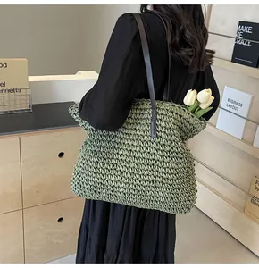 Primer plano del bolso tote de paja verde tejido con correas de hombro de cuero fino