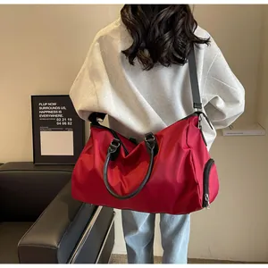 Large red travel bag with side zipper pocket and black shoulder strap shown on model