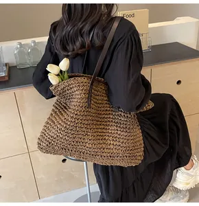 Detalle de la textura tejida del bolso tote de paja con correas de hombro de cuero marrón