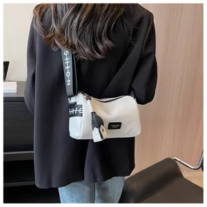 Detail of off-white cylinder bag with textured leather and fashion logo strap