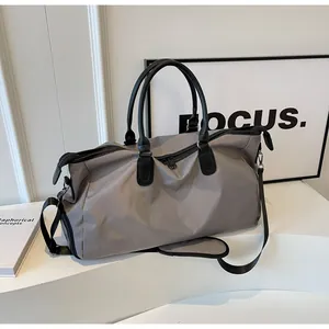 Detail view of large grey travel bag with black handles and adjustable shoulder strap