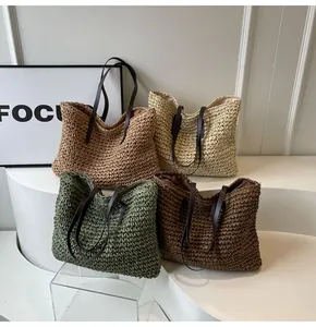 Detalle de cuatro bolsos de mano tejidos en crema, caqui, verde y marrón con asas de cuero