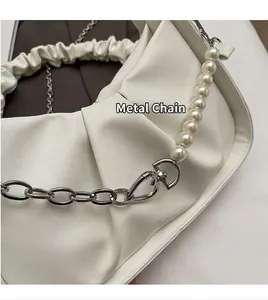 Detail of white ruched cloud bag featuring silver metal chain and pearl shoulder strap