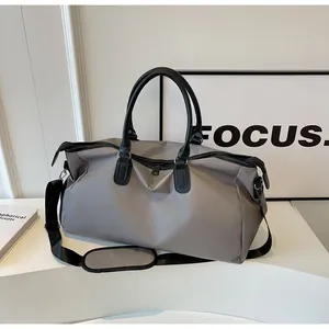 Detail view of grey nylon travel bag with black leather handles and padded shoulder strap