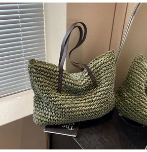 Detalle del bolso tote de paja tejida verde oliva con correas de hombro de cuero marrón