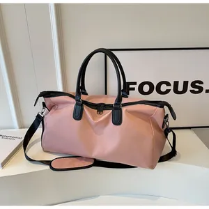 Pink waterproof nylon travel bag with black leather handles and adjustable shoulder strap