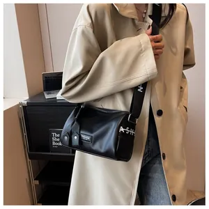 Detailed view of black pebbled leather cylinder bag with branded wide strap on model