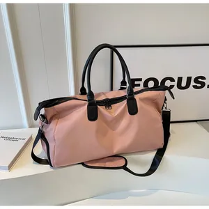 Detail of light pink travel bag with black shoulder strap on white display stand