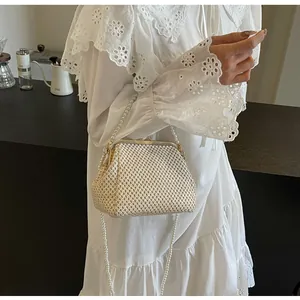Detail shot of beige woven evening shell bag with pearl strap on lace dress