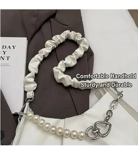 Detail of white ruched cloud bag featuring decorative pearl chain and heart metal buckle