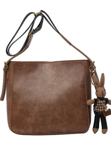 Minimalistische bruine leren emmertas met retro textuur en vintage konijnenpop bedeltje