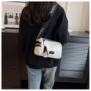 Detail of white cylinder bag with branded wide strap shown on model shoulder