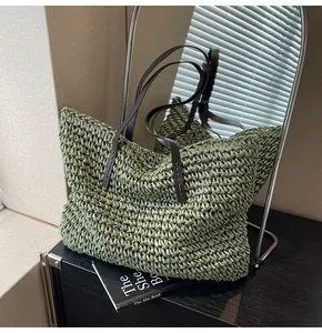 Detalle del bolso tote trenzado verde con asas de cuero marrón y textura de paja tejida