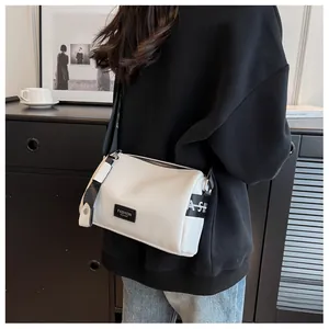 Detail of white leather crossbody bag with wide printed strap and black fashion label