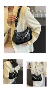Detail of black pleated cloud hobo bag featuring pearl chain and heart metal buckle