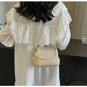 Detail of cream woven shell bag featuring elegant pearl strap and metallic gold clasp