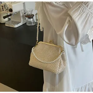 Detailed view of straw-woven clutch bag with double pearl chain and vintage metal clasp