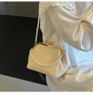 Detail view of woven shell bag with pearl handle and vintage metal clasp on a model